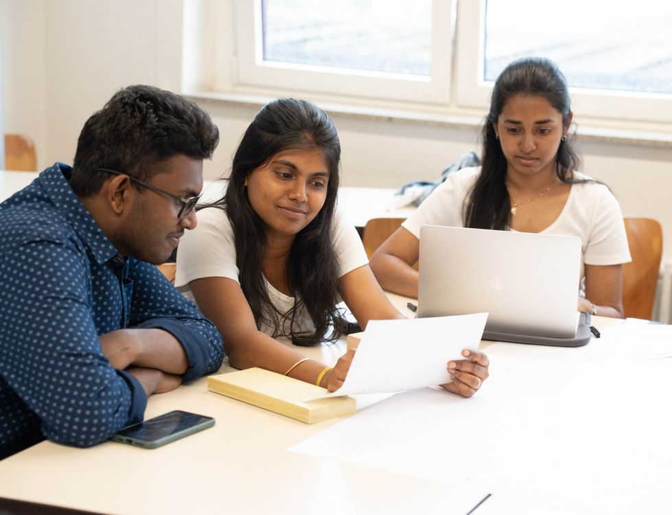 College students collaborating with documents and a laptop